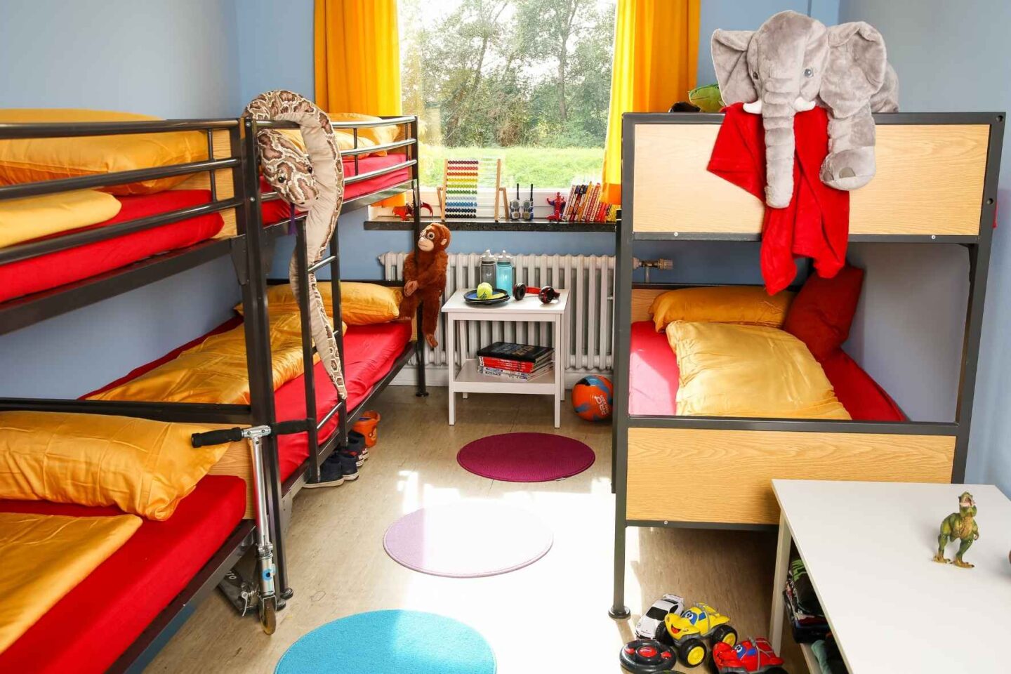 Helles, bunt eingerichtetes Vierbettzimmer in der Freiluftschule Bunthausspitze mit Stockbetten und Spielzeug.