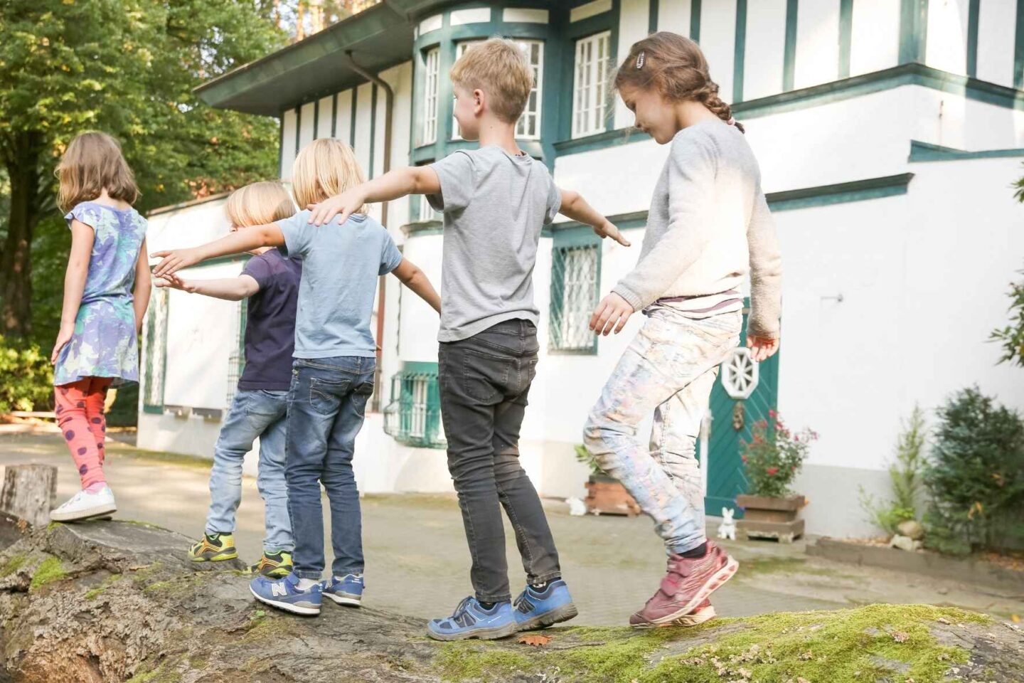 Gruppe von Kindern die auf einem Baumstamm balancieren.