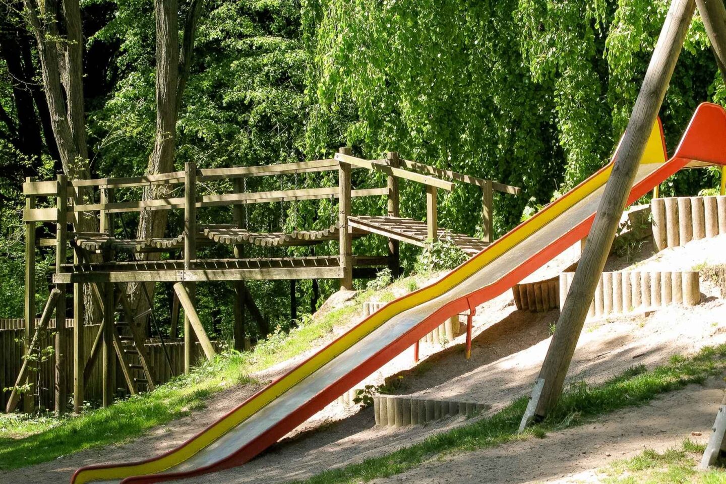Spielplatz der Freiluftschule Wittenbergen, ausgestattet mit Rutsche und Klettergerüsten inmitten der Natur.