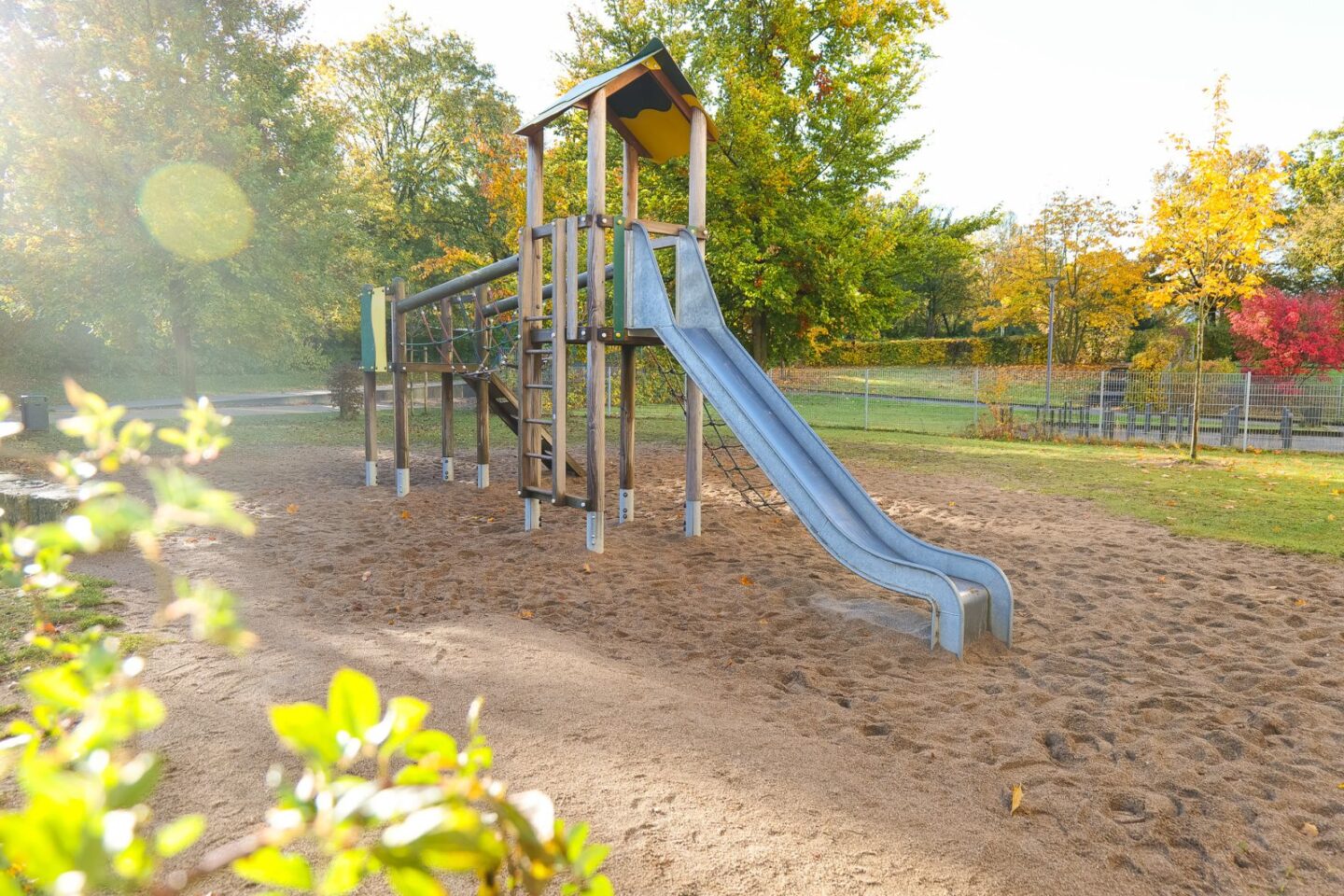 Kinderspielplatz mit einer großen, metallenen Rutsche und Sandboden im Außenbereich der Kita Barlsheide, perfekt für Bewegung und Spielspaß.