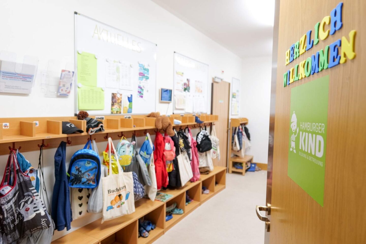 Garderobe der Kita Barlsheide mit Haken und persönlichen Fächern für die Sachen der Kinder, sowie einem freundlichen Begrüßungsschild.