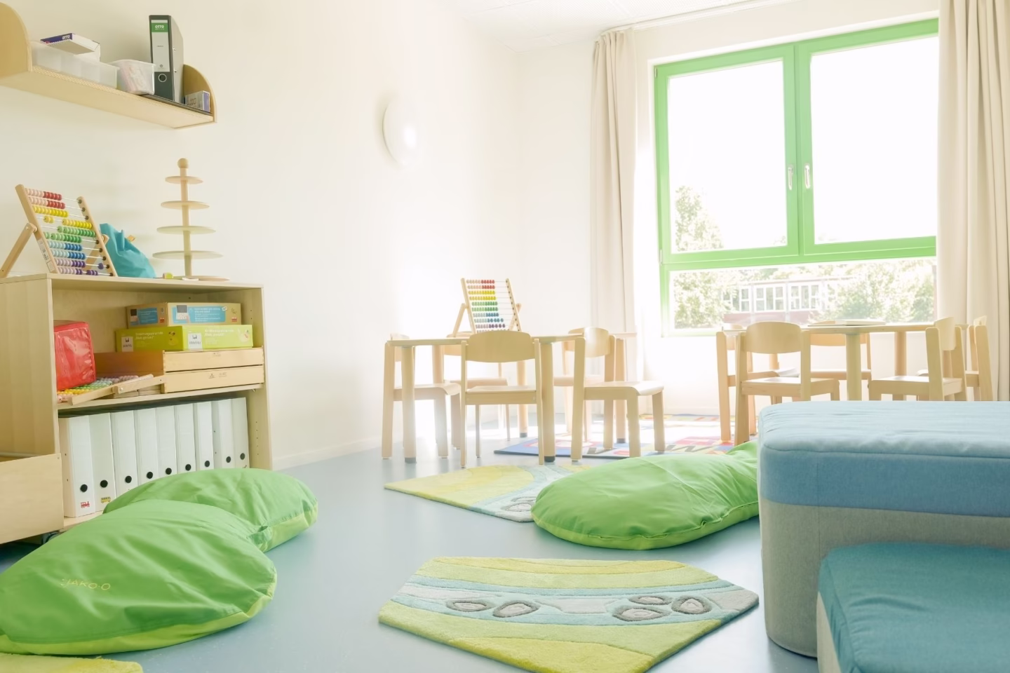 Kindergarten-Sitzecke mit bequemen Sitzmöglichkeiten für Kinder, kleinen Tischen und Tagesbett
